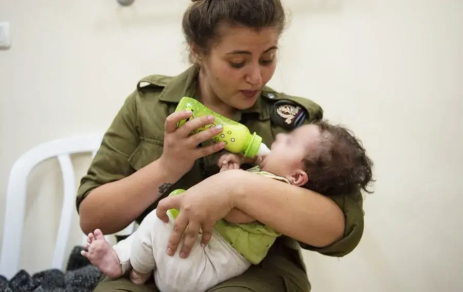 IDF soldier feeds a Syrian baby in Israel as part of the Operation Good Neighbor - the army's humanitarian aid program to assist Syrians