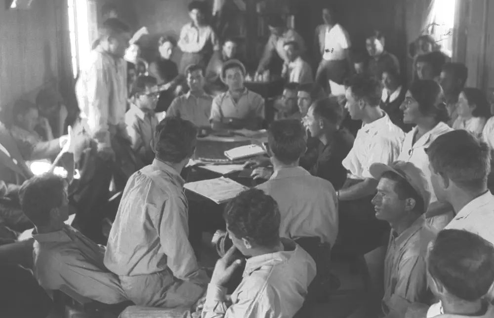 Members gathered in the library during a general assembly Members gathered in the library during a general assembly. It's an excellent image illustrating the classic kibbutz tradition of community decision-making